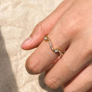 Bague élégante ondulée en acier inoxydable doré avec strass sur une main à la plage