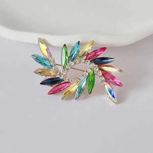 Detail of multi-color crystal brooch with radiant sunburst design and gold plating