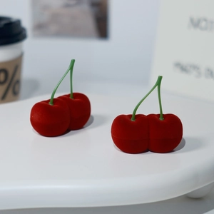 Detalle del joyero con forma de cereza en terciopelo rojo sobre soporte blanco