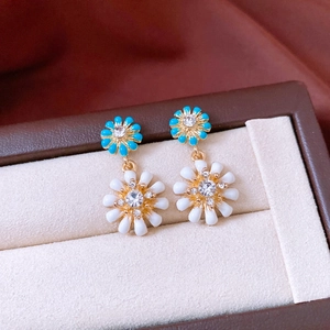 Gros plan de boucles d'oreilles fleurs doubles avec émail bleu et détails en cristal