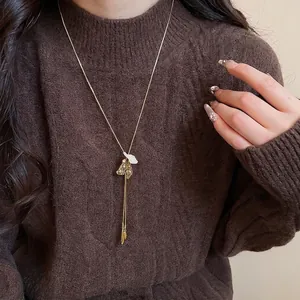 French vintage gold petal pendant necklace with long tassels on a knitted sweater
