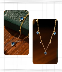 Macro detail of a square blue gemstone pendant on a gold chain inside a jewelry box