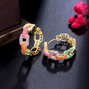 Macro shot of gold hoop earrings with multi-colored crystals and delicate chain details