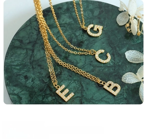 Macro detail of gold plated titanium steel necklaces with crystal letter pendants G C E B