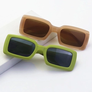 Close-up of retro square sunglasses in green and pink thick frames on white stands