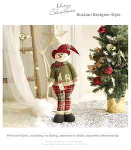 Detailed view of standing plush snowman with green knit sweater and plaid pants