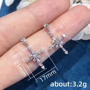 Silver cross drop earrings with white cubic zirconia crystals, 21mm size on navy velvet