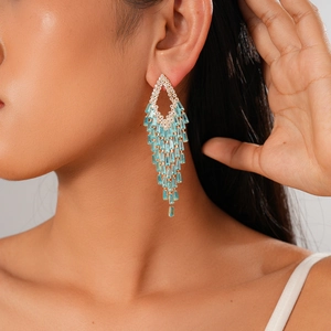 Close-up of geometric tassel earring with blue crystals worn by a professional model
