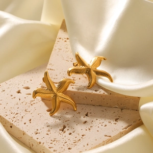 Boucles d'oreilles étoile de mer dorées en acier inoxydable sur satin blanc et pierre