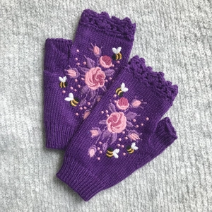 Detail of purple knit fingerless gloves with floral and bee embroidery on wool fabric
