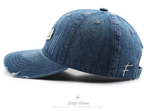 Close-up of dark blue washed denim baseball cap with vintage distressed holes and embroidery