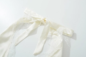 Detail eines cremeweißen Satinbands mit zarter Spitze an einem eleganten Neckholder-Kleid