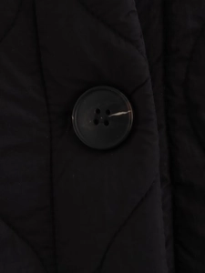 Detailaufnahme einer schwarzen Steppjacke mit großem dunklem Knopf und Steppmuster-Textur