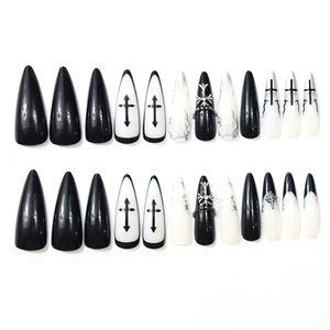 Gothic stiletto press-on nails with black and white cross designs and metallic charms