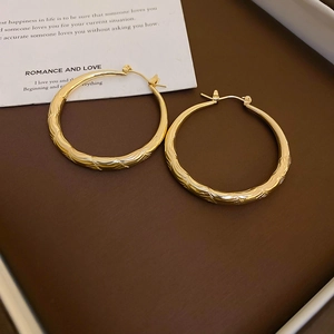Macro detail of gold round hoop earrings with elegant hammered diamond texture