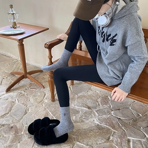 Detail of warm grey thermal knit socks paired with black plush slippers for winter wear