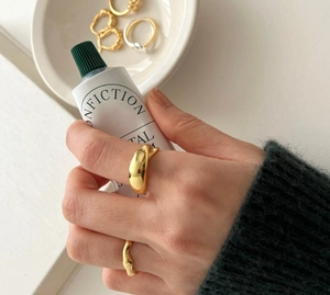 Detailed view of polished gold wide oval ring and slim wavy band on hand