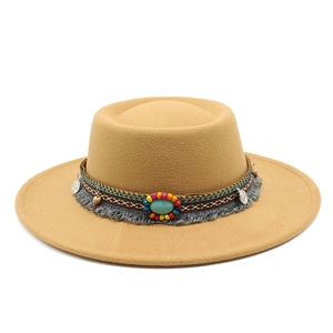 Détail d'un chapeau en laine camel avec ruban bohème, pierre turquoise et pompons