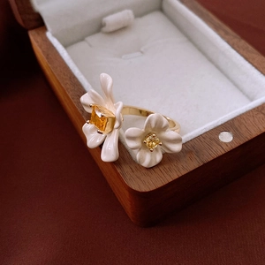 Macro detail of gold-plated double flower ring featuring white petals and yellow crystals