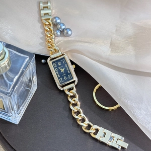 Macro detail of luxury rectangular blue dial watch with diamond bezel and gold chain strap