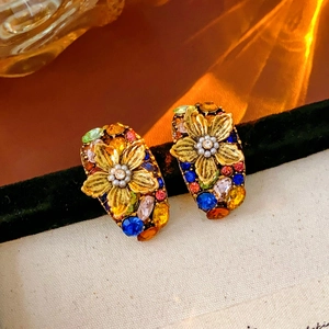Detailed shot of vintage gold flower earrings with colorful rhinestones on velvet