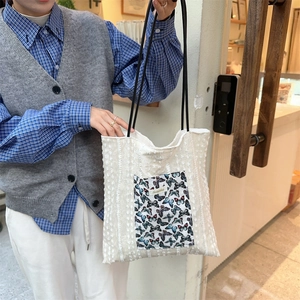 Detail of off-white canvas tote bag with butterfly print pocket and rope straps