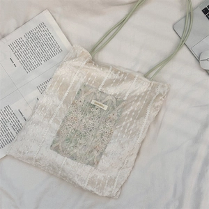 Détail du sac fourre-tout en velours avec poche avant en dentelle beige et anses vertes