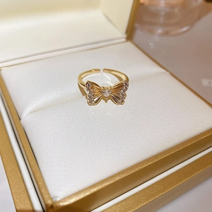 Close-up of golden bow-shaped open ring with cat eye stone and pearls in a jewelry box