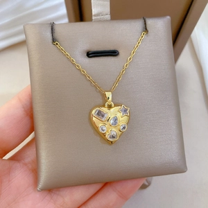 Detail of heart pendant with sparkling crystals and drop shape stones on gold necklace