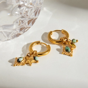 Detail of gold hoop earrings featuring green stone and star pendants on white background