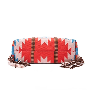 Detail of bohemian woven tote bag with geometric tribal patterns and colorful fringes