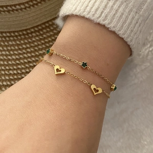 Détails de bracelets superposés avec cœur doré et breloque étoile émeraude