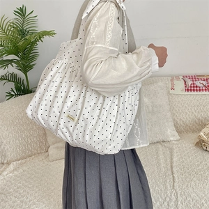 Close-up of white polka dot canvas shoulder bag featuring ruffled pleats and large capacity