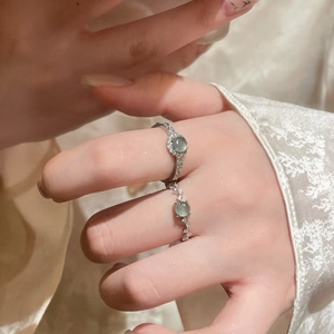 Close-up of elegant silver flower rings with light green zircon stones on model's fingers