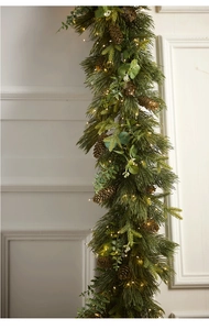 Close-up of lighted Christmas garland with pine needles, eucalyptus leaves and cones