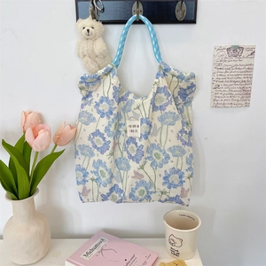 Detail of floral canvas tote bag showing blue woven handles and sozakka label