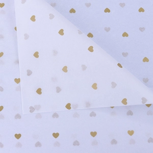 Close-up of white tissue paper with gold heart patterns for floral and gift wrapping