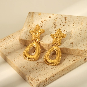 Détail de boucles d'oreilles pendantes dorées vintage avec texture martelée et étoiles
