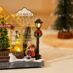 Detail of glowing Christmas greenhouse resin ornament with warm LED lights and figurines