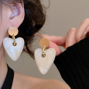 Detailed view of heart earrings with white marble texture resin and golden studs
