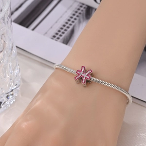 Close-up of pink enamel Pisces zodiac charm on silver snake chain bracelet