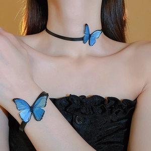 Close-up of blue butterfly choker and bracelet set worn on a model with black bands