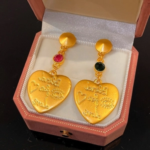 Dettaglio dei pendenti vintage a cuore con gemme rosa in una confezione regalo rosa