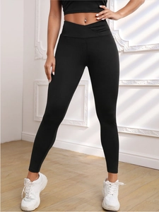 Detail of high waisted yoga pants with crossover waistband design and peach lift effect