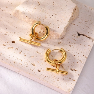 Minimalist gold T-bar drop hoop earrings presented on a natural stone surface