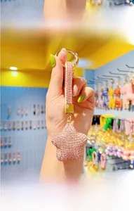 Pink rhinestone star keychain with gold hardware and studded strap held in hand