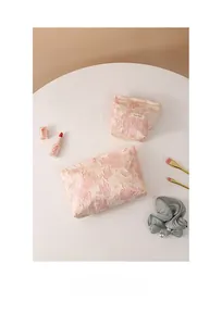 Detailed top view of pink floral lace makeup bags in two sizes on a white table