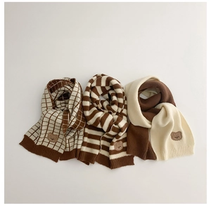 Detail of knitted kids scarves with bear embroidery in plaid, striped and beige tones