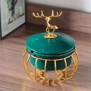 Detail of luxury emerald ceramic jar with golden deer head handle on decorative metal base