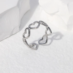 Detailed view of polished stainless steel ring with continuous hollow heart patterns